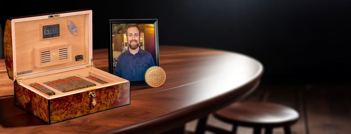 Cigar humidor with digital display on a wooden table, featuring a man's face on a screen.